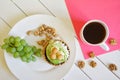 A bunch of grapes, pistachios, walnuts mug with black coffee on a white wooden background next to a pink napkin. Country breakfast Royalty Free Stock Photo