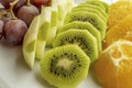 Bunch of grapes, sliced kiwi, apple and orange fruits in white plate Royalty Free Stock Photo