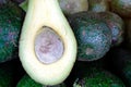 Bunch of green Avocados. One of them is opened that the stone and the pulp are visible Royalty Free Stock Photo