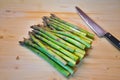 Bunch of green fresh asparagus or spargel in german on the choping plate with kitchen knife