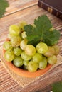 Bunch of green grapes with fresh vine leaf on a bowl with closed Holy Bible on wooden table Royalty Free Stock Photo