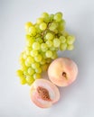 A bunch of green grapes and two pink peaches, one sliced, isolated on a white background. View from above Royalty Free Stock Photo
