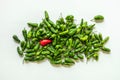 A bunch of green padrÃÂ³n peppers and a lone red one on smooth white surface Royalty Free Stock Photo