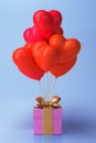 Bunch of heart shaped foil balloons and gift on pink background. Royalty Free Stock Photo