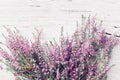 Bunch of heather flower calluna vulgaris, erica, ling on shabby wooden table top view. Pastel greeting card in vintage style.