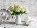 Bunch of hydrangeas, cup of green tea, teapot on the table. Cozy home still life Royalty Free Stock Photo