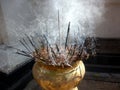 Bunch of incense sticks in a brass vessel burning and releasing aromatic smoke