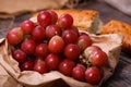 A bunch of juicy large red grapes and fresh crispy wheaten baguette on a table of dark old wooden boards Royalty Free Stock Photo