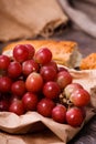 A bunch of juicy large red grapes and fresh crispy wheaten baguette on a table of dark old wooden boards Royalty Free Stock Photo