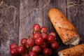 A bunch of juicy large red grapes and fresh crispy wheaten baguette on a table of dark old wooden boards Royalty Free Stock Photo