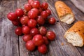 A bunch of juicy large red grapes and fresh crispy wheaten baguette on a table of dark old wooden boards Royalty Free Stock Photo