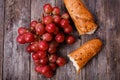 A bunch of juicy large red grapes and fresh crispy wheaten baguette on a table of dark old wooden boards Royalty Free Stock Photo