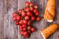 A bunch of juicy large red grapes and fresh crispy wheaten baguette on a table of dark old wooden boards Royalty Free Stock Photo