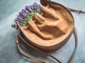 Bunch of lavenders in crossbody leather orange bag. Concrete background. Closeup
