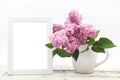 Bunch lilac in vase on wooden table and white frame mock up