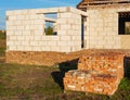 Bunch of lined up old bricks on the pallet on the sunset, unfinished house on the background Royalty Free Stock Photo