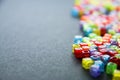 A bunch of little multicolored letters on the surface of a dark background, selective focus