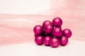 A bunch of magenta painted ornaments on a white surface mattress with a textured pink background Royalty Free Stock Photo