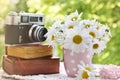 Bunch of marguerite flowers and vintage books and camera in the garden