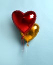 Bunch of metallic red and gold color heart shaped foil balloons on pastel light blue background. Set of air balloons, love