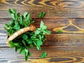 bunch of mint in a small wicker basket on old burnt wooden background Royalty Free Stock Photo