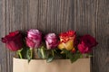 Bunch of multicolor rose flowers in paper envelope over wooden b Royalty Free Stock Photo