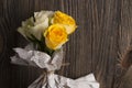 Bunch of multicolor rose flowers wrapped in newspaper over wooden background. Royalty Free Stock Photo