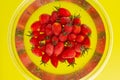 Bunch of Napa grape cherry tomatoes in water closeup, inside a clear bowl, on yellow background Royalty Free Stock Photo