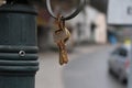 Bunch of old, rusty metal keys in key ring hanging on hook. Blurry town background Royalty Free Stock Photo