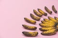 Bunch of overripe spoiled mini-bananas on a pale pink background