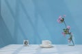 Bunch of peach blossoms, cup of coffee, alarm clock on desk, sunlight through window on home office desk, minimalist Royalty Free Stock Photo