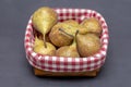 A bunch of pears are lying in a wicker wooden basket on a dark background, close-up, side view, checkered fabric.