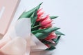 A bunch of pink tulips on white background with a gift box. Spring concept. Greeting card with flowers