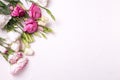 Bunch of pink and white eustoma flowers on white textured background.