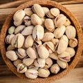 a bunch of pistachios nuts in a brown cork plate on a wooden background. Royalty Free Stock Photo
