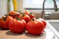 a bunch of plump tomatoes next to a sink Royalty Free Stock Photo