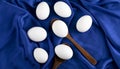 Bunch of raw eggs with wooden spoon on blue sateen cloth