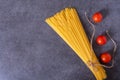 Bunch of raw Italian pasta with cherry tomatoes isolated on stone grey background. Royalty Free Stock Photo