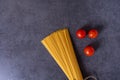 Bunch of raw Italian pasta with cherry tomatoes isolated on stone grey background. Royalty Free Stock Photo