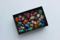 Bunch of raw semi-precious colored quartz stones in a black box top view Royalty Free Stock Photo