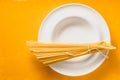 Bunch of raw spaghetti on the white plate on the yellow background top view Royalty Free Stock Photo