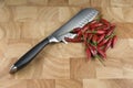 Bunch of red chilli peppers on a timber chopping board with a silver knife Royalty Free Stock Photo