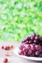 Bunch of red grapes on ceramic plate against green blur background. space for text Royalty Free Stock Photo