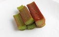 A bunch of red-green rhubarb stalks with water drops on a white background