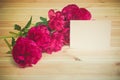 Bunch of red peonies and empty card for your text on wooden surface. Selective focus Royalty Free Stock Photo