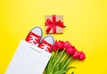 bunch of red tulips, red gumshoes, cool shopping bag and beautiful gift on the wonderful yellow background Royalty Free Stock Photo