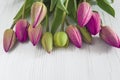 Bunch of red tulips with waterdrops on white wooden background