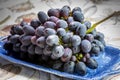 Bunch of ripe blue-black table grape with leaf served on blue plate as dessert Royalty Free Stock Photo