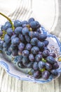 Bunch of ripe blue-black table grape with leaf served on blue plate as dessert Royalty Free Stock Photo