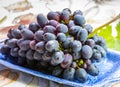 Bunch of ripe blue-black table grape with leaf served on blue plate as dessert Royalty Free Stock Photo